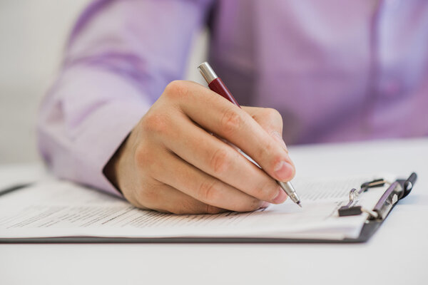 The hand hold a black pen on note book and data reported papers.