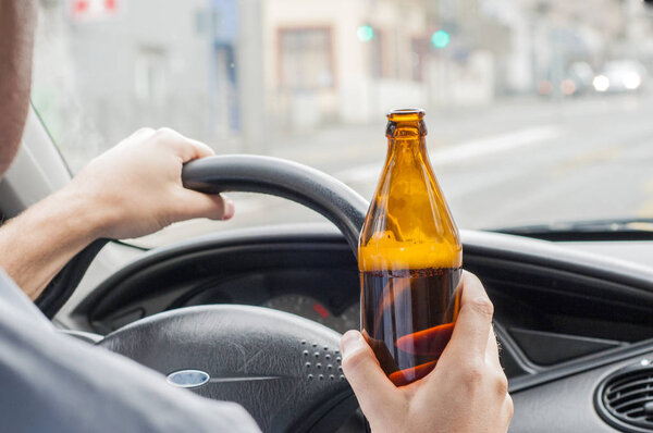 Close-up Of Man Holding Beer Bottle While Driving Car