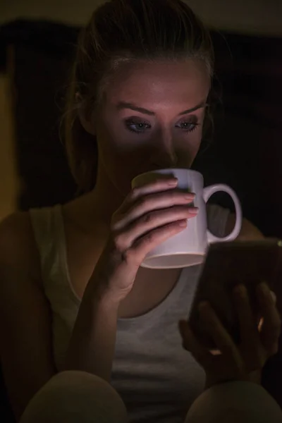 Smart telefon och kaffekopp i flickor händer sitter på ett trägolv — Stockfoto