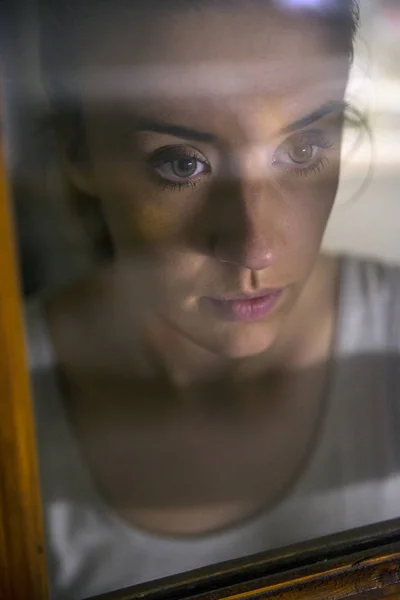 Donna triste che guarda la pioggia che cade da una finestra a casa o in hotel — Foto Stock