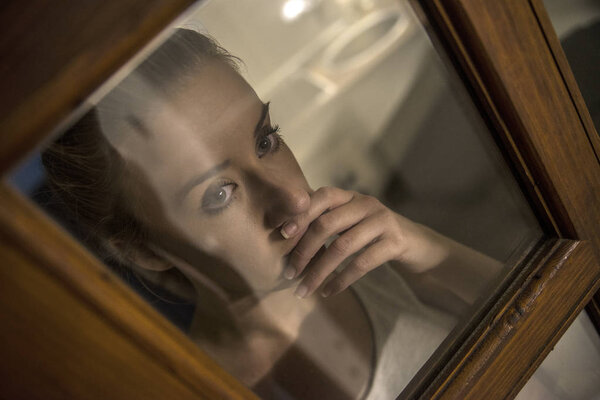 Одинокая девушка у окна думает о чем-то
