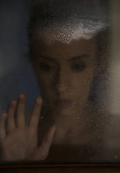Πορτρέτο της η γυναίκα ψάχνει μέσα από το παράθυρο σε μια βροχερή μέρα — Φωτογραφία Αρχείου