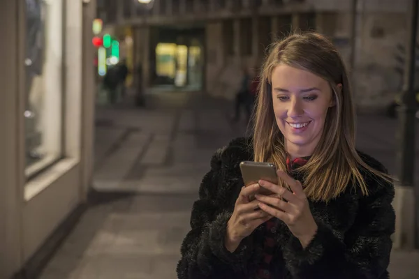Женщина с мобильного телефона, городской фон ночного освещения — стоковое фото