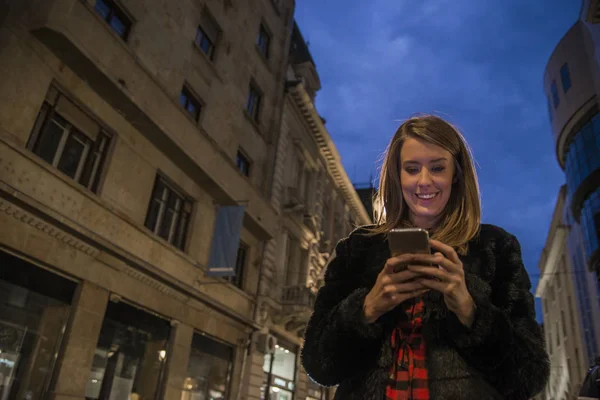 Kadın kısa mesaj telefon sesleri gece okuyun. Akıllı telefon mobil şehirde geceleri kullanan kadın — Stok fotoğraf