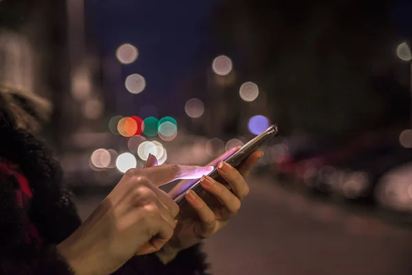 Woman using her mobile phone, city skyline night light background — Stock Photo, Image