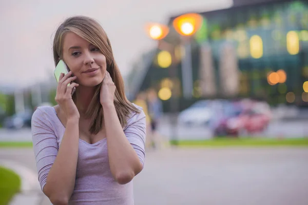 Chica feliz usando un teléfono inteligente en un parque de la ciudad, Retrato de mujer joven feliz con teléfono inteligente en sus manos — Foto de Stock