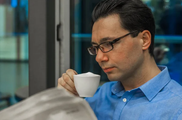 Mi godo il tempo libero per un caffè e qualche notizia. uomo d'affari che legge il giornale mentre beve una tazza di tè caldo al latte durante l'ora di pranzo in mensa . — Foto Stock