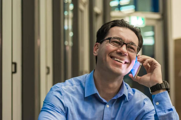 Primo piano di un uomo d'affari sorridente che utilizza un moderno smartphone, Giovane uomo felice che lavora nel suo ufficio e tiene il cellulare — Foto Stock