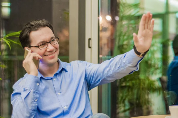 Sorridente giovane uomo che parla al telefono e mostra gesto di saluto — Foto Stock