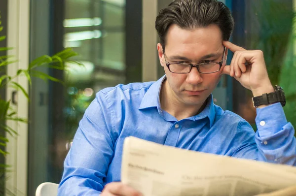 Un bell'uomo che legge un giornale. Uomo d'affari che legge un giornale mentre beve caffè — Foto Stock