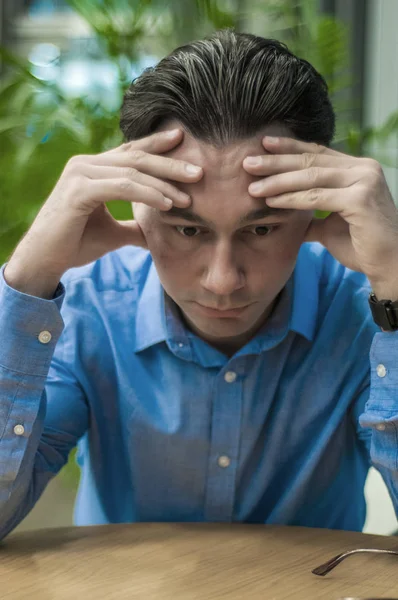 Mi sento male e stanco. Frustrato giovane uomo tenere gli occhi chiusi mentre seduto al suo posto di lavoro in ufficio — Foto Stock