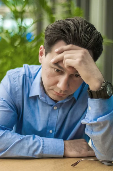 Je me sens malade et fatigué. Jeune homme frustré gardant les yeux fermés alors qu'il était assis sur son lieu de travail au bureau — Photo