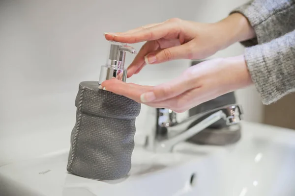 Manos femeninas usando lavador de manos desinfectante dispensador de bomba de gel. Un jabón de manos con loción de bombeo de botella — Foto de Stock