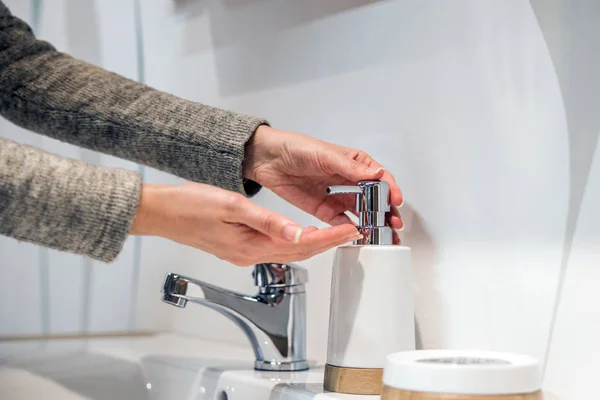 Manos femeninas usando lavador de manos desinfectante dispensador de bomba de gel. Un jabón de manos con loción de bombeo de botella — Foto de Stock