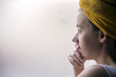 Güzel kız pencere izlerken de ayakta. pencerenin oturan güzel üzücü yalnız kız eksik