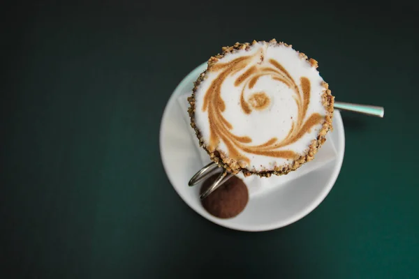 Glass of coffee over black background. Cup of hot  coffee and coffee crop. Cappuccino glass cup with milk foam