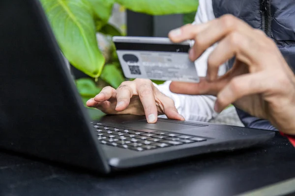 Man holding a credit card and typing. On-line shopping on the internet using a laptop. Close Up Of A Man Shopping Online Using Laptop With Credit Card