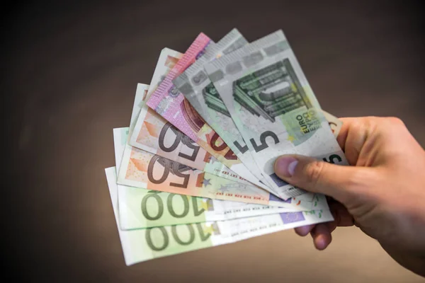 Siyah arka plan üzerinde bir sürü para, el tutan el a yelpaze-in farklı miktarda Euro tutan el izole euro ile adam elini euro para — Stok fotoğraf