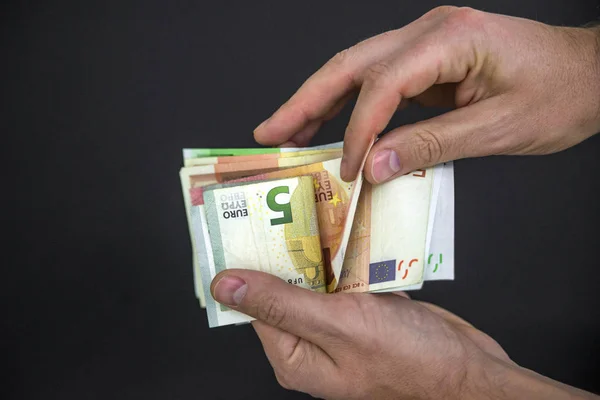Man hand with euro isolated on black background, Hand holding out a fan of euros of different amounts, Hand holding a lot of money, Hand hold euro money