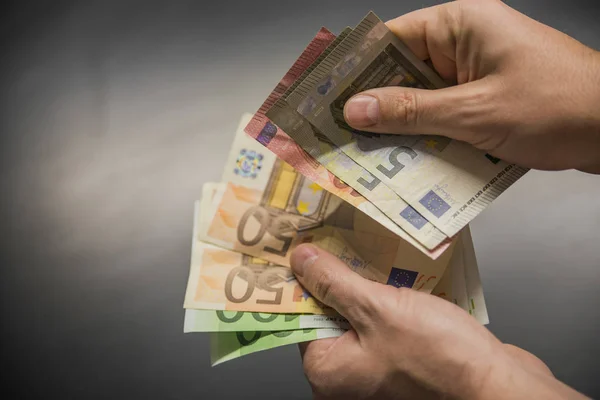 Az ember kezét euro elszigetelt fekete háttér, kezében egy rajongó-ból különböző összegű, euró, kezében egy csomó pénzt, kézzel tartsa euró pénz — Stock Fotó