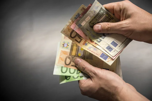 Uomo mano con euro isolato su sfondo nero, Mano tirando fuori un ventilatore di euro di diversi importi, Mano con un sacco di soldi, Mano con denaro in euro — Foto Stock