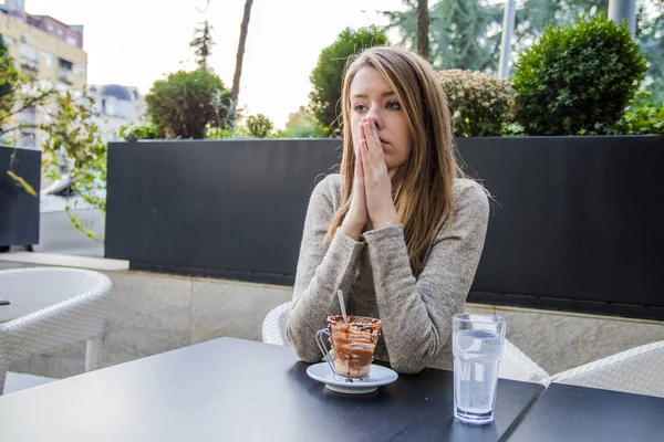 Portrait of young unhappy stressed beautiful female sitting in modern urban cafe, drinking coffee with frustrated expression. Portrait of depressed teenage girl sitting in coffee shop. Thoughtful concept. — Stock Photo, Image