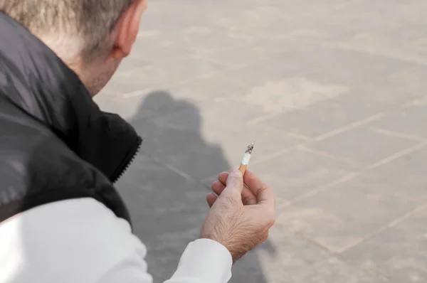 El hombre fuma el cigarrillo en la calle. hombre fumando afuera en un entorno urbano, mirando hacia otro lado —  Fotos de Stock