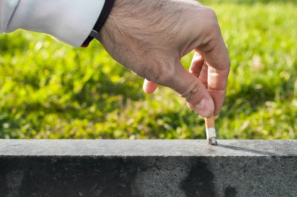 Mão de um jovem que apaga o cigarro. O conceito deixou de fumar. Um homem a apagar um cigarro. Composição conceitual sobre parar de fumar, a mão do homem extingue um charuto. A mão de um jovem extingue o cigarro em uma escada — Fotografia de Stock