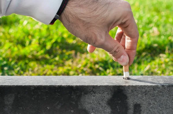 Mão de um jovem que apaga o cigarro. O conceito deixou de fumar. Um homem a apagar um cigarro. Composição conceitual sobre parar de fumar, a mão do homem extingue um charuto. A mão de um jovem extingue o cigarro em uma escada — Fotografia de Stock