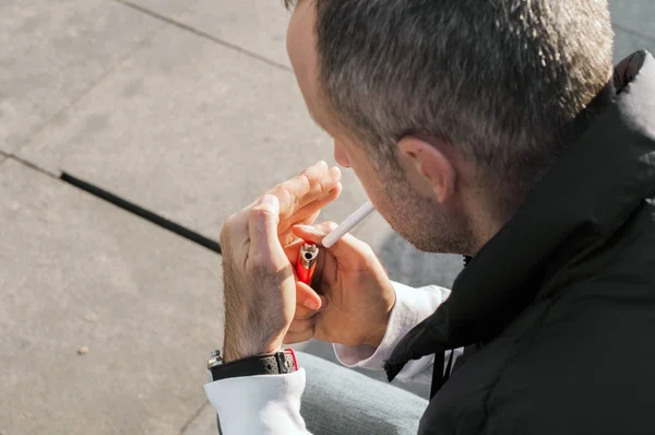 Mann zieht Zigarette aus Packung und zündet sich an Mann zündet sich Zigarette an, Außenprofil-Porträt mit selektivem Fokus — Stockfoto