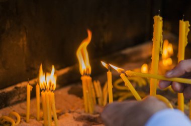 Adam el ışık mumlar bir kilise, mumlar ve yeni bir muma koyarak el.