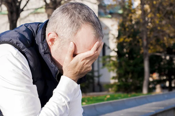 Perfil lateral destacó joven empresario sentado fuera de la oficina corporativa sosteniendo la cabeza con las manos mirando hacia abajo. Emoción humana negativa sentimientos de expresión facial. hombre estresado. retrato de emoción — Foto de Stock