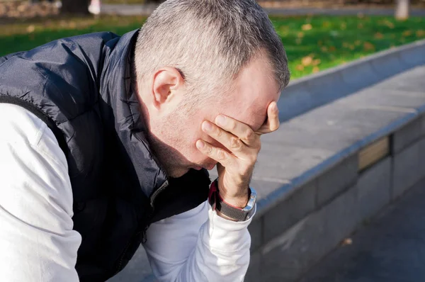 Bankrupt businessman. stressed young business man, resting face  on fist, isolated background of trees outside. Negative human emotion facial expression feelings.