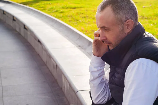 Portrait d'homme parlant sur téléphone portable en plein air, beau jeune homme souriant et parlant au téléphone. Jeune homme joyeux dans une conversation joyeuse au téléphone avec espace de copie. Portrait d'homme heureux et joyeux utilisant un téléphone intelligent en plein air . — Photo