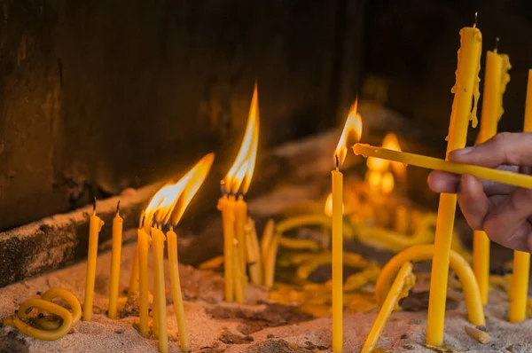 Hombre mano encendiendo velas en una iglesia, velas y la mano poniendo una vela nueva . —  Fotos de Stock