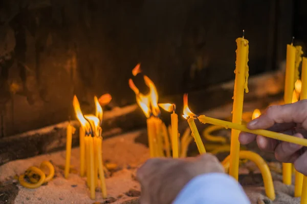 Hombre mano encendiendo velas en una iglesia, velas y la mano poniendo una vela nueva . —  Fotos de Stock