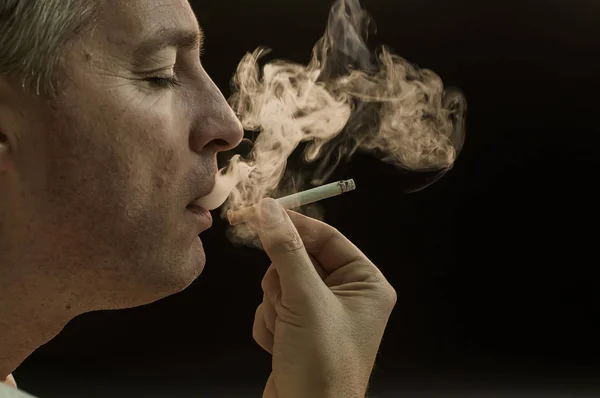 Mann raucht Zigarette auf schwarzem Hintergrund, schöner junger Mann raucht Zigarette, mysteriöser Mann mit Zigarre und Rauch isoliert auf schwarzem Hintergrund — Stockfoto