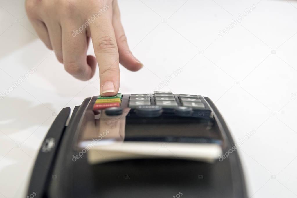 credit card reader machine on white background. Card machine or pos terminal with inserted blank white credit card isolated on white background. Hand and fingers entering pin with a hand held pin pad.