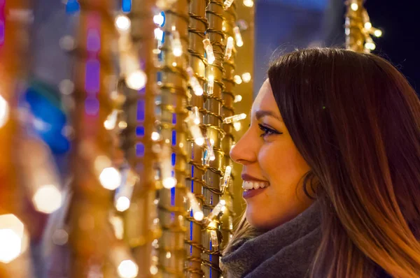 Joven mujer feliz caminando por la noche con decoraciones navideñas. Hermosa chica turística caminando en la calle de la ciudad ocupada — Foto de Stock