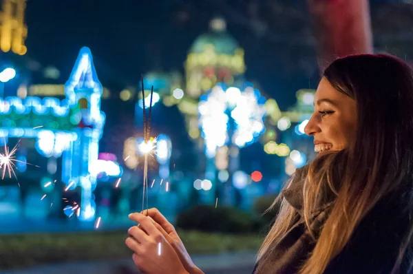 大晦日を祝う彼女の手で線香花火を保持している女性。イベント、新年を祝っている若い女性が来ています。彼女はきらびやかな線香花火をつかまってください。. — ストック写真