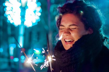 Kadın kış açık havada. Maytap yeni yıl kutlama tutan gülümseyen kadın