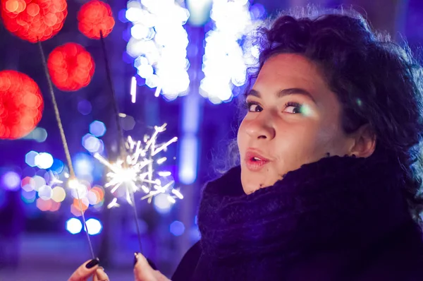 Mujer sonriente sosteniendo chispa en la celebración de Año Nuevo. Mujer joven sosteniendo una bengala encendida para celebrar el año nuevo — Foto de Stock