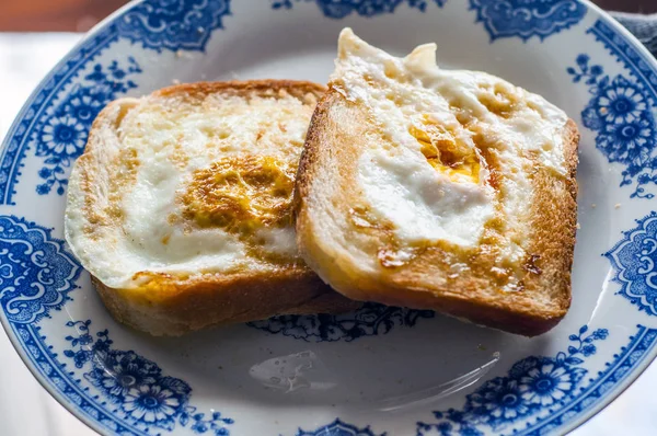 Bir tabak altın kahverengi yumurtalı ekmek. Yumurtalı ekmek tabakta doğal ışık ile fotoğraflandı. Tereyağı ve yumurta ile altın yumurtalı ekmek. ekmek ile Servis Kahvaltı