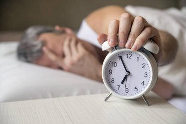 Bir çalar saat sabah 7 de dönüm yatakta yatan adam. Çekici bir adam onun yatak odasında yatmak. Kızgın adam tarafından bir çalar saat onun yatak odasında uyanmış olmak