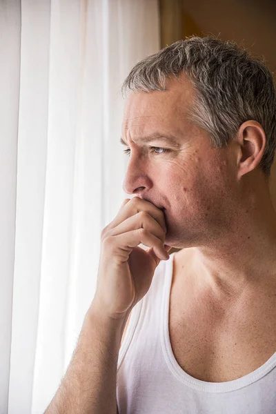 Sad man looking out the window. Feeling hopeless. Depressed mature man standing near the window. man suffering for depression — Stock Photo, Image