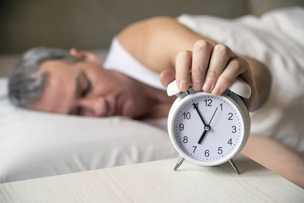 Gewekt. Hand schakelt de wekker op ochtend wakker. zachte huidtoon. Man wordt door een wekker in zijn slaapkamer gewekt uitgeput — Stockfoto