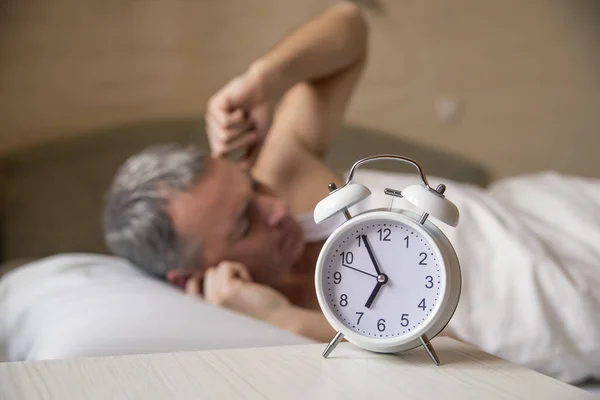 Een woedende man graag wakker in de ochtend. Boze man in bed gewekt door een geluid. Gewekt — Stockfoto