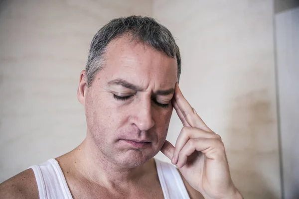 Beau jeune homme touchant sa tête avec une main se sentant mal à la tête forte, photo de près. Je me sens fatigué. stress, maux de tête, désespoir, chagrin et concept de personnes — Photo