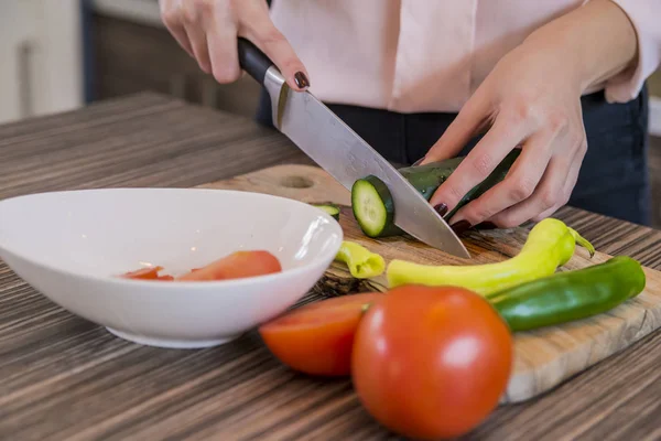 Young woman cutting vegetables in kitchen at home, Human hands cooking vegetables salad in kitchen. Lovely girl preparing low-calorie snack from fresh vegetables