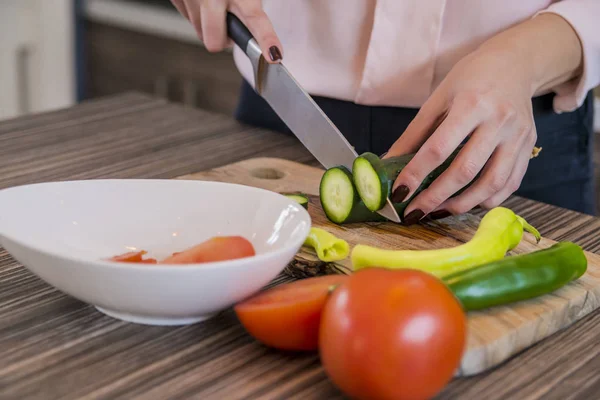 女人在她的厨房里切蔬菜。切黄瓜。健康的一餐和素食概念. — 图库照片
